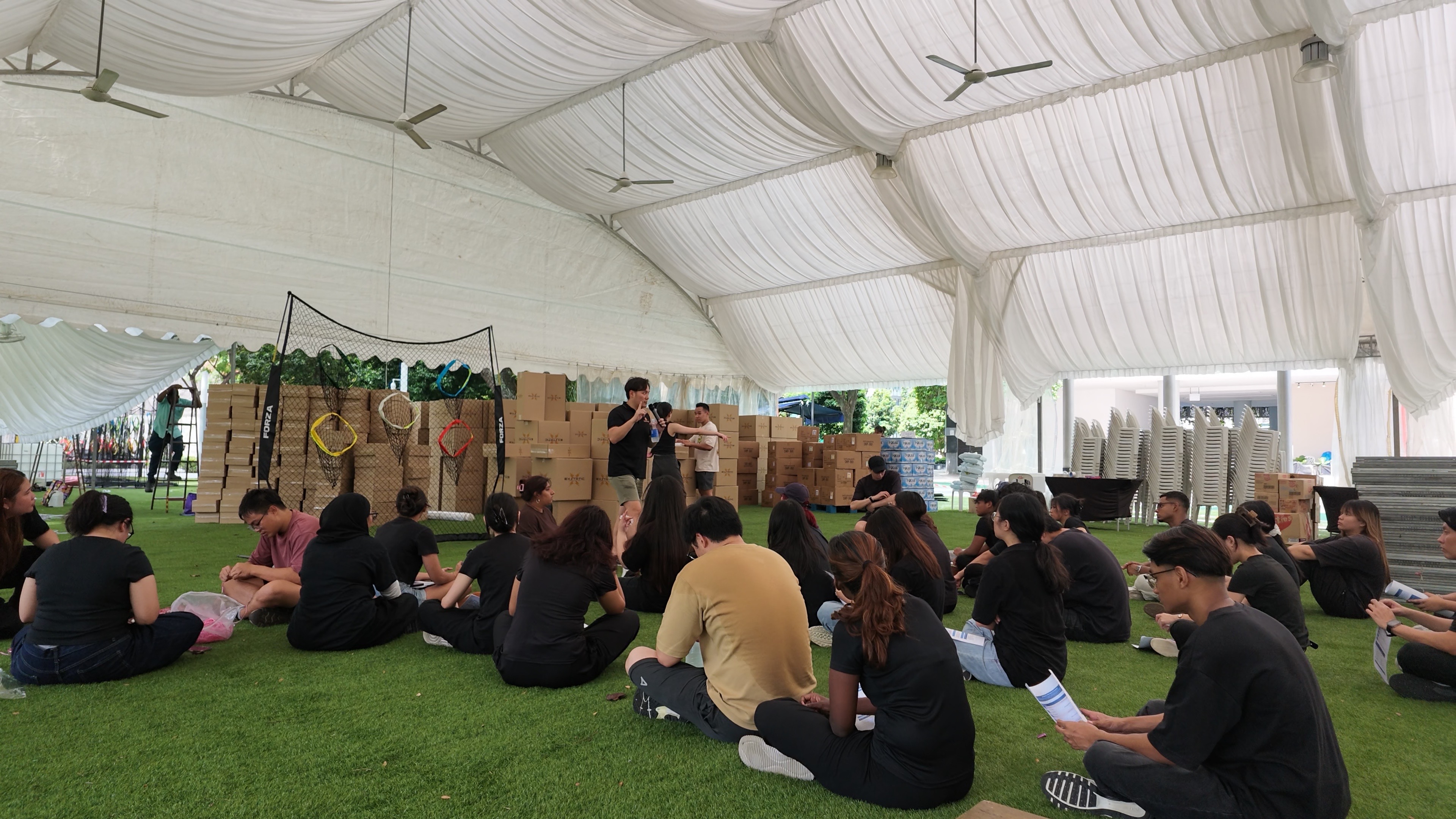 Crew seated for a pre-event briefing under a marquee